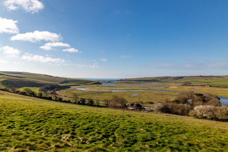 A view over the Cuckmere Valley towards the sea, with a blue sky overheadの写真素材