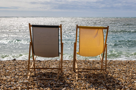 Deckchairs on the pebble beach in the sunshine, at Lyme Regis in Dorset