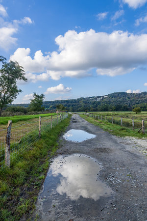 Puddles on a pathway in the Sussex countryside, with a blue sky overheadの写真素材