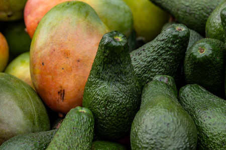 A display of mangoes and avocado's on a market stall, with selective focusの写真素材