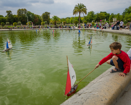 Paris, France, August 18, 2015 - A boy plays with a sailboat in the pond at the Luxembourg Gardens on a summer afternoon.のeditorial素材