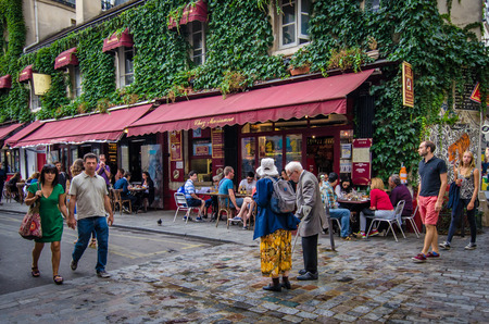 Paris, France, August 16, 2015 - An older couple walk along Rue Hospitalires St. Gervais in front of Chez Marianne, a popular restaurant in the historic district of Marais.のeditorial素材