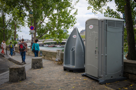 Paris, France August 15, 2015 - People walk by public toilet facilities on Quai d'Orleans on the island of Ile St-Louis. More than 400 public toilet facilities scattered about the city.のeditorial素材