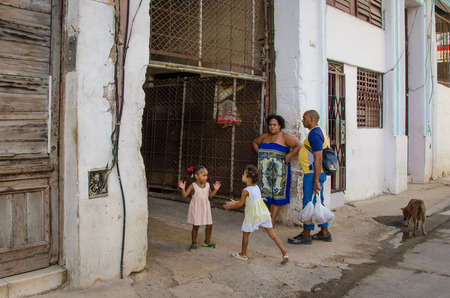 Havana, Cuba, June 19, 2016 - Two girls are playing a clapping game in front of their home, one of thousands of deteriorating and decaying buildings in La Habana Vieja.のeditorial素材