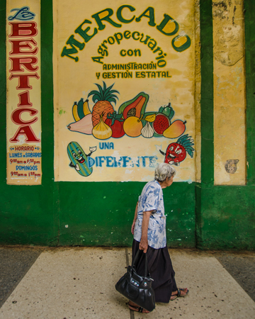 HAVANA - CUBA JUNE 12, 2016: An old woman walks by Mercado, a shop in the historic La Habana Vieja neighborhood selling fruit and vegetables.のeditorial素材
