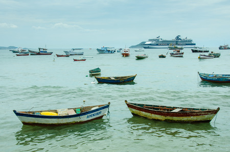 Buzios, Brazil, February 25, 2017 - Variety of fishing boats are at anchor in the harbor of the popular resort city on the Atlantic coast with a cruise ship in the distance.のeditorial素材
