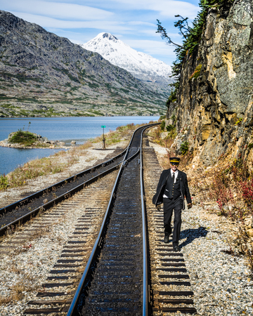 Skagway, Alaska, September 10, 2017 - A conductor for the White Pass & Yukon Route Railroad linking the port with Whitehorse, Yukon walks behind the train checking the rails.のeditorial素材