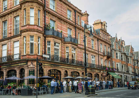 London, England, August 18, 2018 - : Patrons of The Audley, a popular bar in the Mayfair district, spill out into the streets on a Friday evening, meeting friends at the end of the work week.のeditorial素材