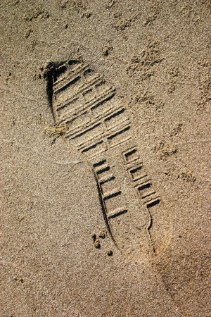 Close up of amber sand with shoe stamp in hot summer.