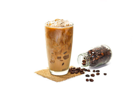 Iced coffee with milk in glass and coffee beans on white background