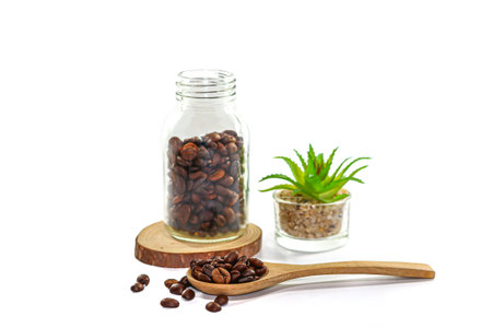Coffee beans in wooden spoon and glass jar on white backgroundの写真素材