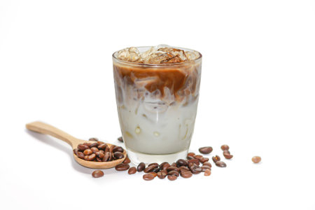 Iced coffee with milk in a glass and coffee beans on white background