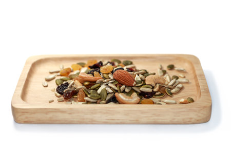 Mix of nuts and dried fruits on wooden plate, isolated on whiteの写真素材