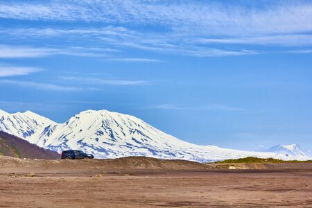Valley with yellow grass covered with snow on a background of mountains, blue sky.の写真素材