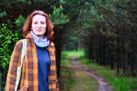 Russia Moscow region June 2020. a young girl in a stylish coat stands on a forest path. against the background of a beautiful forest corridor with a well-trodden path colorのeditorial素材
