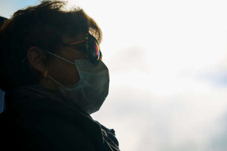 Moscow June 2020 portrait of a woman in a Medetsin mask at the glass of a train car. behind the glass shines a bright sun. The corona virus epidemic in Russiaのeditorial素材