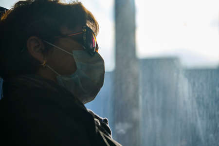 Moscow June 2020 portrait of a woman in a Medetsin mask at the glass of a train car. behind the glass shines a bright sun. The corona virus epidemic in Russiaのeditorial素材
