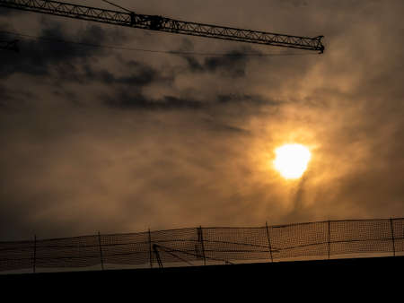 silhouette of a construction crane behind a sunsetの写真素材