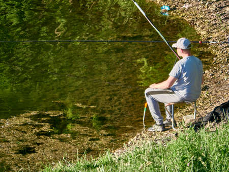 russia 2021 moscow. A fisherman sits with a fishing rod on the bank of the river colorのeditorial素材