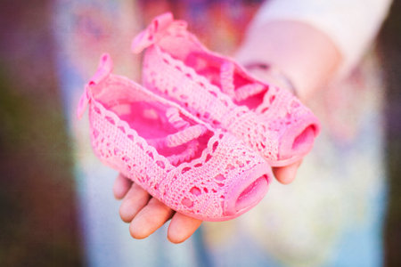 bright pink baby shoes in womans handの写真素材