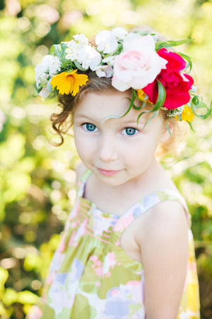 Little girl in flower wreath in the gardenの写真素材