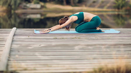 Sportswoman do yoga on wooden platformの写真素材