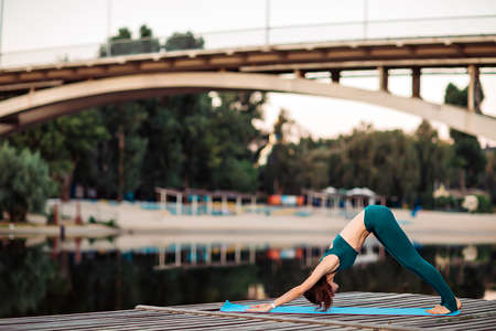 Sportswoman do yoga on wooden platformの写真素材