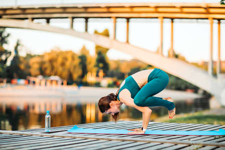 Sportswoman do yoga on wooden platformの写真素材