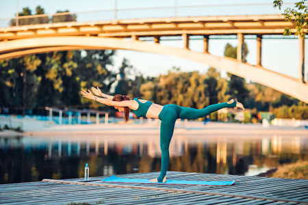 Sportswoman do yoga on wooden platformの写真素材