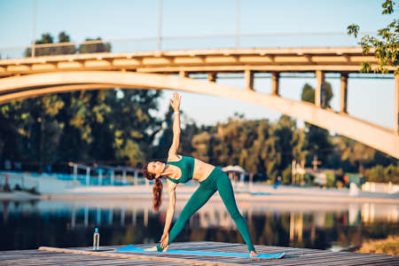 Sportswoman do yoga on wooden platformの写真素材