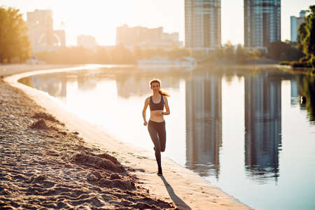 sportswoman run on riverbank at sunriseの写真素材