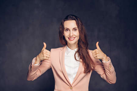 caucasian woman show thumbs up on dark backgroundの写真素材