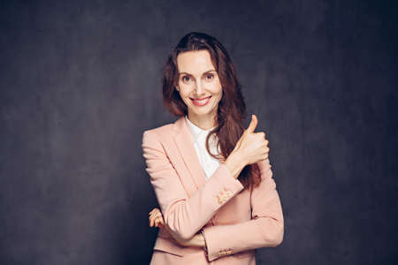 caucasian woman show thumb up on dark backgroundの写真素材