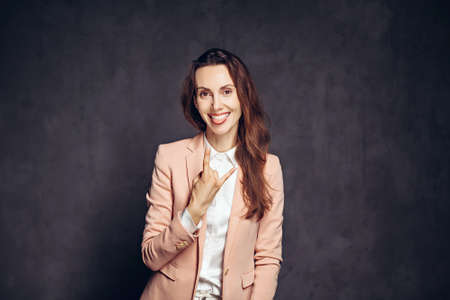 Adult woman show rock gesture on dark backgroundの写真素材