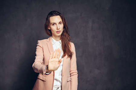 caucasian woman show stop sign on dark backgroundの写真素材