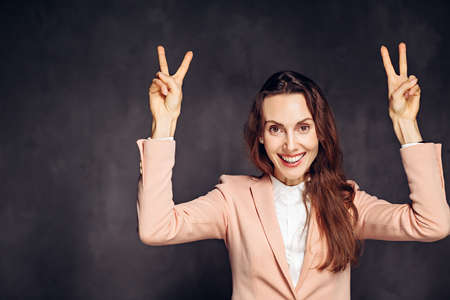 woman show victory gesture on dark backgroundの写真素材