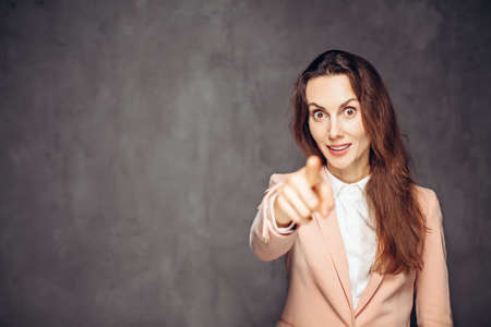 Adult woman point with finger on dark backgroundの写真素材
