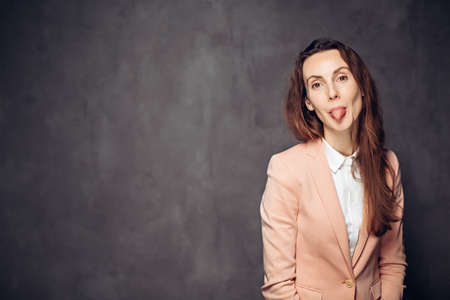 Adult woman sticking out tongue on dark backgroundの写真素材
