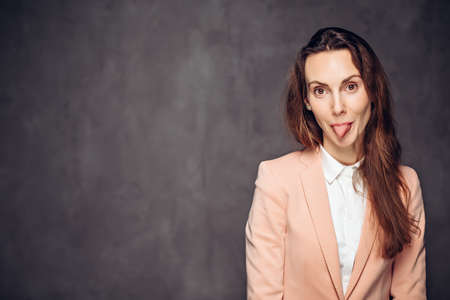 Adult woman sticking out tongue on dark backgroundの写真素材