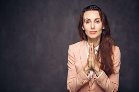 Adult woman with please gesture on dark backgroundの写真素材