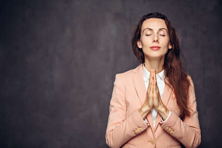 Adult caucasian woman pray on dark backgroundの写真素材