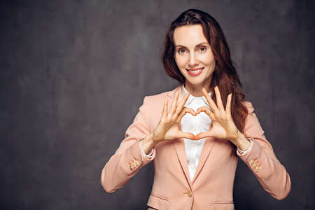 caucasian woman show heart sign on dark backgroundの写真素材
