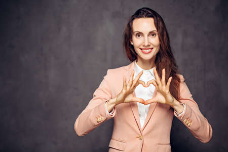caucasian woman show heart sign on dark backgroundの写真素材