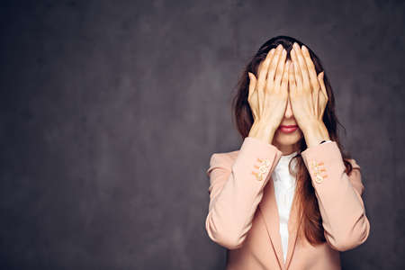 caucasian woman covering eyes on dark backgroundの写真素材