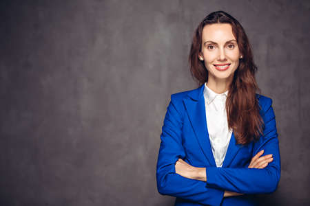Smiling woman with crossed arms on dark backgroundの写真素材