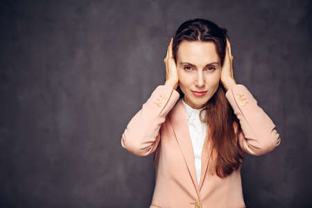 caucasian woman covering ears on dark backgroundの写真素材