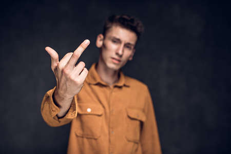 young man show middle finger on dark backgroundの写真素材