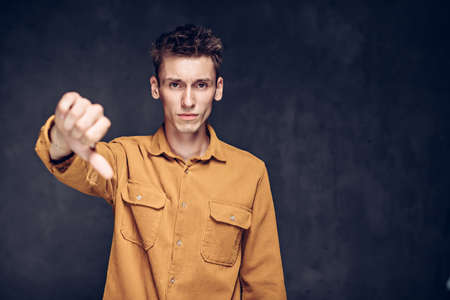 caucasian man show thumb down on dark backgroundの写真素材