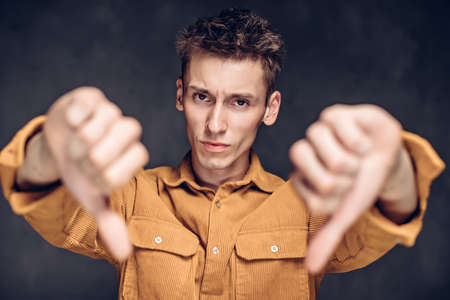 caucasian man show thumbs down on dark backgroundの写真素材