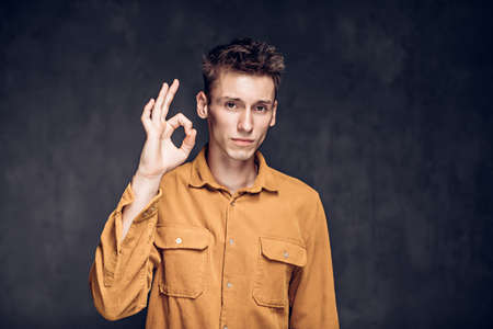 caucasian man show Ok sign on dark backgroundの写真素材